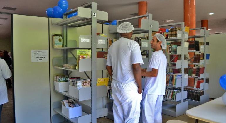 Dois trabalhadores estão parados do lado de estantes de livros