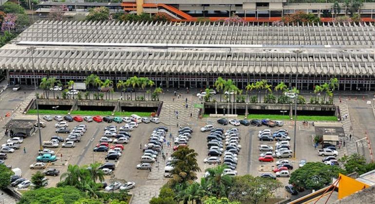 Foto: Breno Pataro/PBH Imagem aérea do erminal Rodoviário Governador Israel Pinheiro (TERGIP), com prédio retambular e estacionamento com mais de trinta carros á frente, durante o dia.