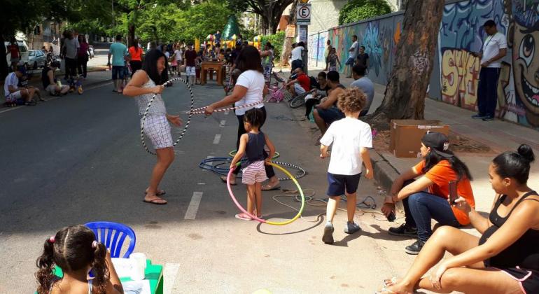 Crianças e adultos se divertem com brincadeiras oferecidas no BH é da gente, na Avenida Silva Lobo. Pessoas com bambolês.