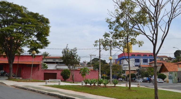 Praça revitalizada: árvores, plantas, grama, bancos e postes de luz.