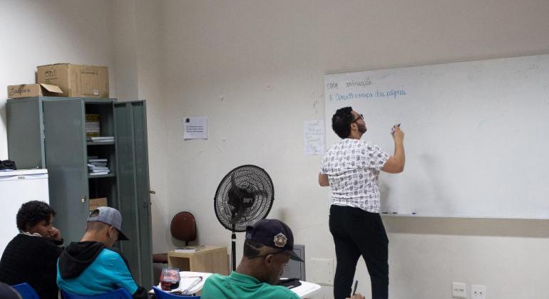 Três alunos e um professor em uma sala de aula