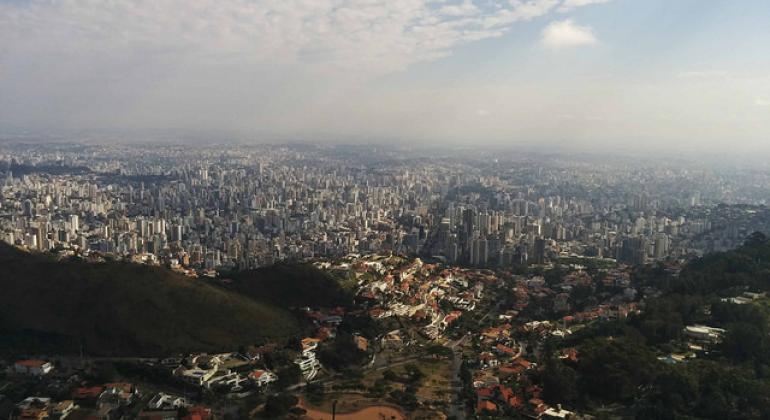 A foto mostra a vista de Belo Horizonte a partir do Parque da Serra do Curral, em um dia de céu claro com poucas nuvens.