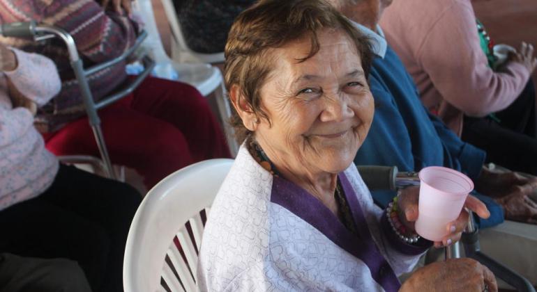 Prefeitura oferece cuidados e lazer para os idosos dentro e fora das ILPIs. Foto: Zaira Magalhães/PBH Cinco idosos sentados em cadeiras plásticas e segurando copos; uma das senhoras sorri.