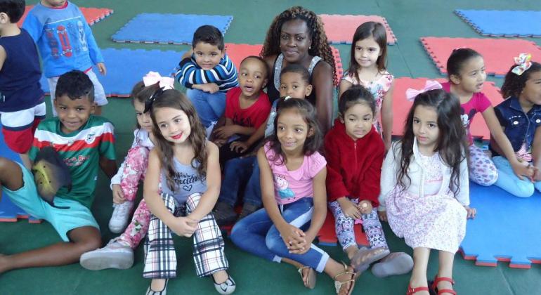 Professora incentiva crianças da Educação Infantil a cuidar do meio ambiente. Foto: Sidney Procópio/PBH Professora e cerca de quinze crianças sentadas em tatami infantil