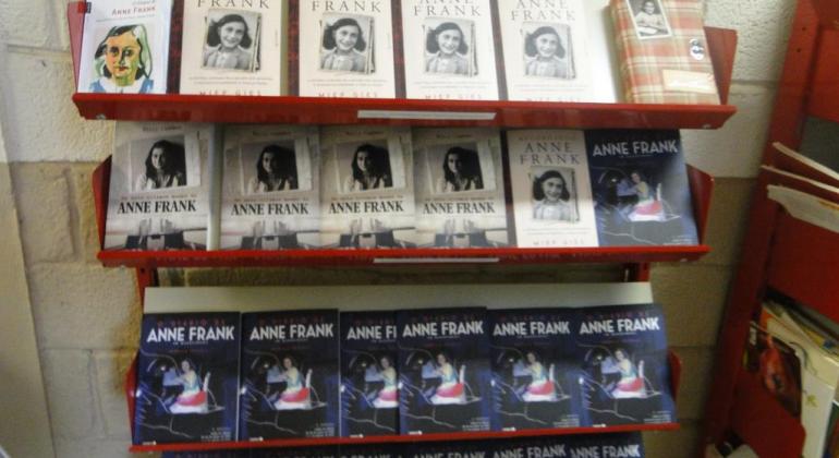 Prateleira com cerca de vinte e cinco livros, de diversos modelos, sobre Anne Frank