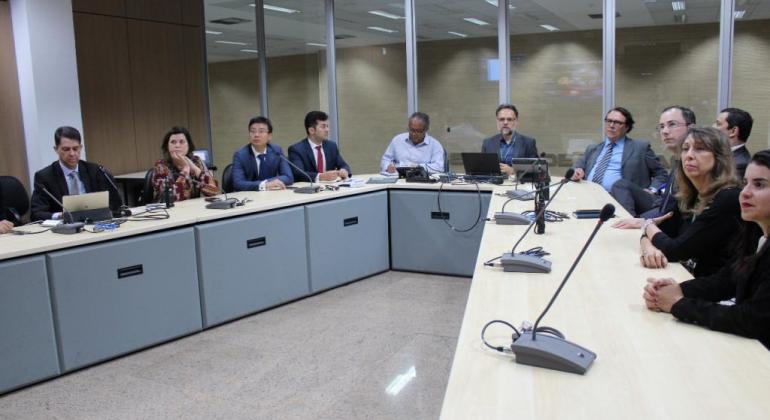 Mesa em U composta por cerca de 10 pessoas, entre autoridades municipais e chinesas