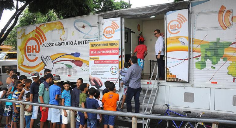 Regional Pampulha recebe o Projeto Conexão Aberta A imagem mostra a lateral de uma carreta transformada em laboratório de informática. Ha cerca de dez pessoas em um fila para entrar no espaço projetado pela Prodabel