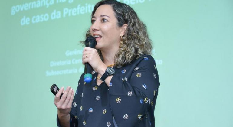 A diretora Denise Barcellos apresenta a experiência de Belo Horizonte. Imagem da diretora Denise Barcellos durante sua palestra.