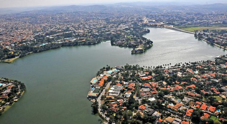 A foto mostra a vista aérea da Lagoa da Pampulha em um dia de céu claro com poucas nuvens. 