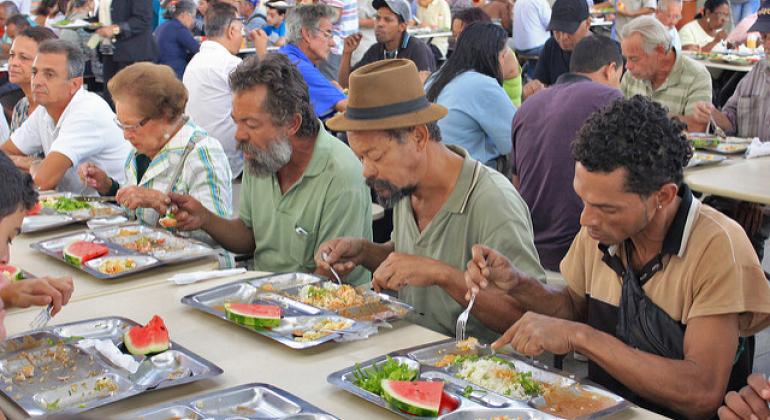 A foto mostra cerca de 30 pessoas sentadas em mesas do Restaurante Popular VI em Belo Horizonte. 