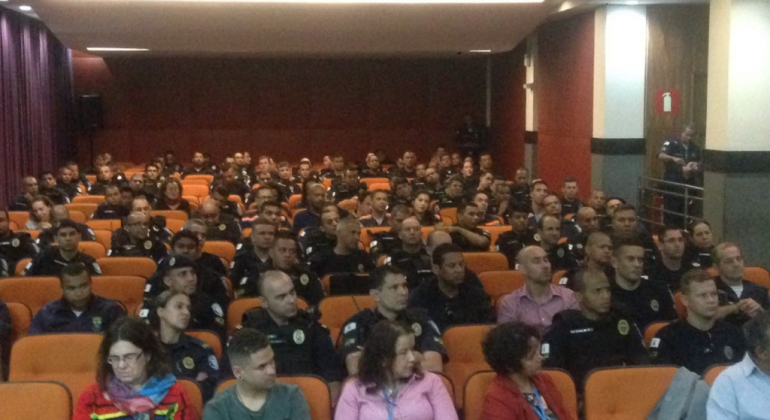 Debate apresenta estudo sobre gangues no ambiente urbano A foto mostra um auditório onde há cerca de 50 pessoas sentadas, entre elas agentes da guarda municipal.
