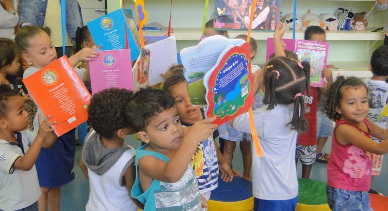 Crianças de 2 ou 3 anos brincam com livros em Umei