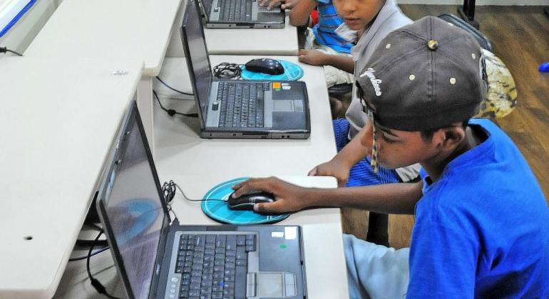Duas crianças usam o computador