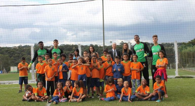 Estudantes de Belo Horizonte assistem aos jogos de América e do Atlético Crianças com camisas na cor laranja do projeto escola integrada posam com quatro goleiros do time do América