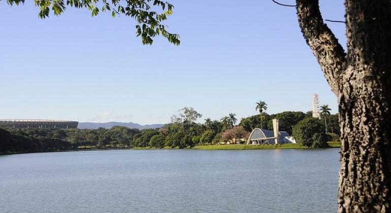 Foto da vista da Lagoa da Pampulha em um dia de céu claro e sem nuvens. Ao fundo a Igreja de São Francisco de Assis.