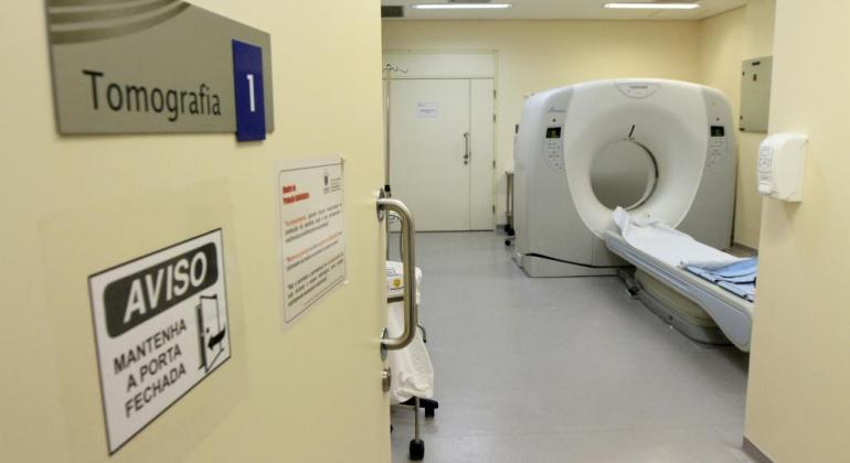 Foto de uma sala de tomografia, indicada com uma placa na porta.