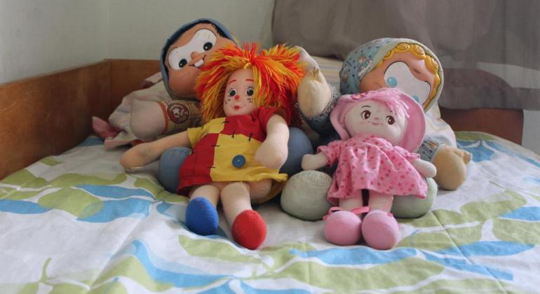 Família Acolhedora oferece acolhimento temporário para crianças e adolescentes. Foto: Debora de Oliveira/PBH Quatro bonecos de pano em cima de uma cama