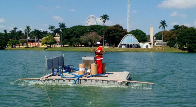 funcionário em plataforma no meio da lagoa da pampulha realiza o processo de limpeza.