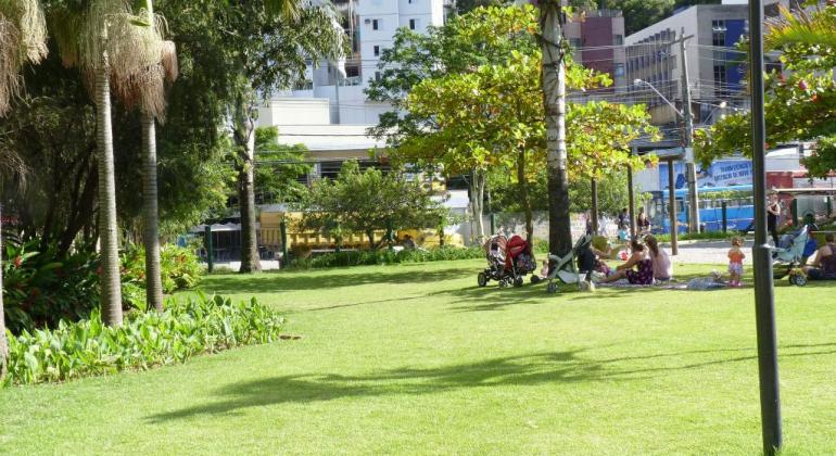 Belo Horizonte tem eventos gratuitos em praças e parques da cidade Parque Aggeo Pio Sobrinho em dia de sol. A grama está bem verde e há pessoas no espaço com carrinho de bebê