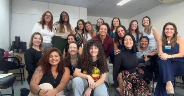 Dezessete mulheres reunidas sorriem.