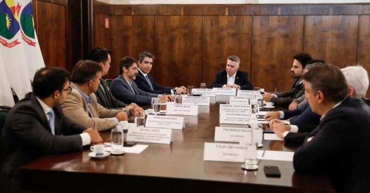 Autoridades sentados à mesa, em reunião