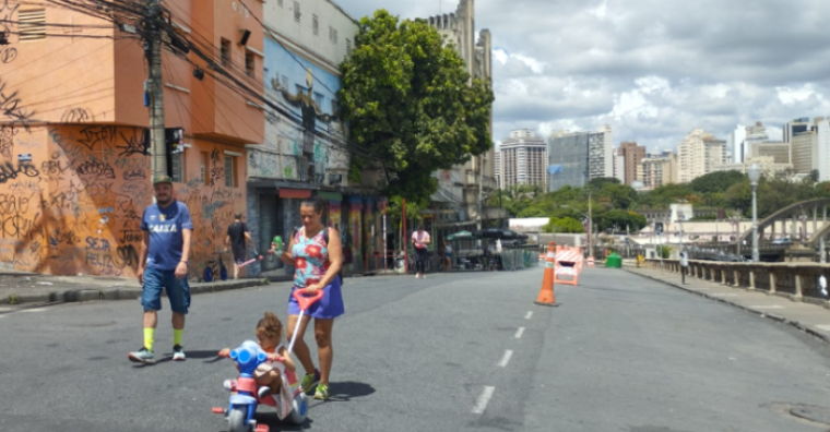 Homem e mulher passeando com uma criança em velotrol na Rua Sapucaí