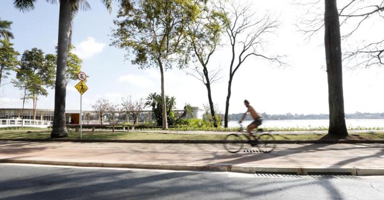 Fotografia da Lagoa da Pampulha, com um ciclista passando rápido em cima da ciclovia.