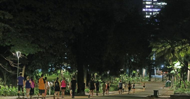 Pessoas fazem caminhada no parque, à noite