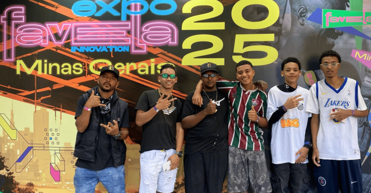 Incubadora do Funk na ExpoFavela 25 Seis jovens sorriem juntos na Expo Favela Minas Gerais 2023, vestindo roupas casuais e fazendo sinais com as mãos.