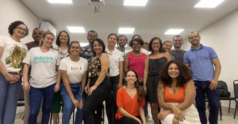 Cerca de 17 pessoas posam para foto em reunião em uma sala