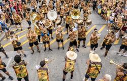 Integrantes da bateria de um bloco de carnaval, em atividade, na rua.