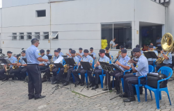 integrantes da guarda municipal sentados em cadeiras azuis se apresentam ao público durante evento
