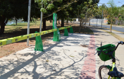 Bicicleta com cestinho e cores fortes próxima a estação de compartilhamento em calçada de BH, durante o dia. 