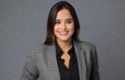 Nathália Coelho - Diretora de Eventos Mulher de cabelos pretos usa camisa preta e blaser cinza. Sorri para a foto.