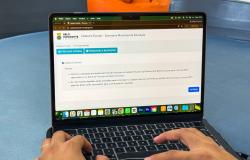 As mãos de uma pessoa digitam em um notebook aberto na página do cadastro escolar