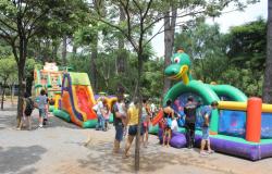 Espaço de lazer com brinquedos infláveis e várias pessoas brincando 