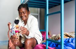 Mulher segura bonecas em um quarto da unidade de acolhimento do Taquaril.
