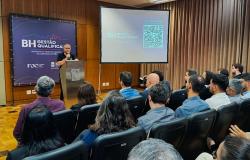 Prefeito Álvaro Damião está de pé, falando ao microfone, para um público formado por secretários e servidores da Prefeitura, durante apresentação do programa BH Gestão Qualificada. Há um banner com a arte do programa e uma tela. Na imagem, parte do público está sentada, de costas, ouvindo o discurso do prefeito.