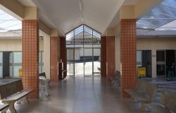 Imagem interna da Capela Velório do Barreiro, com as colunas na entrada do equipamento público, e bancos compondo o cenário.