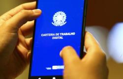 Imagem da Carteira de Trabalho Digital em telefone celular erguido por duas mãos