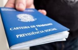 Imagem da Carteira de Trabalho com parte de uma mão segurando o documento