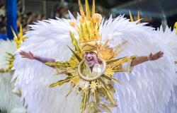 Integrante do Bloco Caricato Estivadores do Havaí posa com fantasia alegórica em tons de amarelo e branco durante o Carnaval de Belo Horizonte.