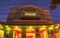 Fotografia da fachada do Cine Santa Tereza ao anoitecer, tirada de baixo para cima. O prédio tem um formato levemente curvado nas bordas por causa do efeito da foto. 