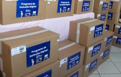 Caixas empilhadas com computadores na cor parda com adesivos em azul escrito Programa de Inclusão Digital