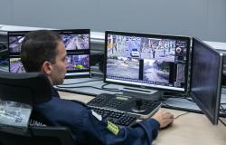 Agente da Guarda Municipal, usando uniforme azul, está de frente para tela do computador fazendo o monitoramento das imagens geradas pelas câmeras do COP-BH.