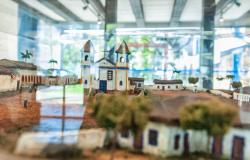 Maquete em vitrine de vidro exibindo o antigo Arraial do Curral del Rei, com destaque para a igreja matriz e pequenas casas históricas.