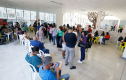 Imagem de sala destinada à espera de pessoas que buscam por vagas de emprego junto à PBH, com cadeiras para acomodações dos interessados e guichês de atendimento.