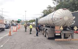 Imagem mostra um caminhão tanque na lateral do Novo Anel sendo ficalizado por fiscais. Na foto há também um homem de jaqueta azul próximo ao caminhão.