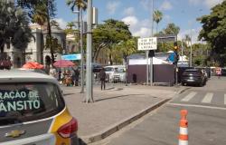 Foto diurna de uma rua na região da Praça da Liberdade, em Belo Horizonte. Em primeiro plano à esquerda, aparece a traseira de uma viatura da BHTrans. À direita, na pista, há um cone de sinalização laranja e branco.