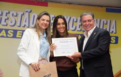 Foto da secretária de Educação, Natália Araújo, ao lado de gestora de escola e do prefeito Álvaro Damião em cerimônia pela melhoria do Ideb
